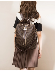 Detail view of stylish brown patterned backpack with gold zippers and adjustable straps