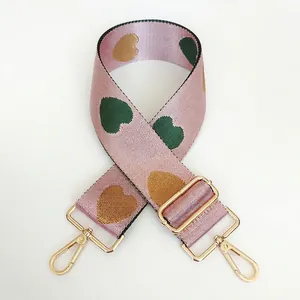 Detail of adjustable nylon bag strap with pink heart pattern and gold swivel hooks
