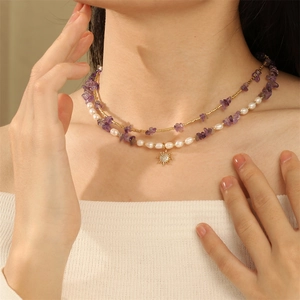 Detail of layered necklace featuring purple stone chips, pearls and gold sun pendant