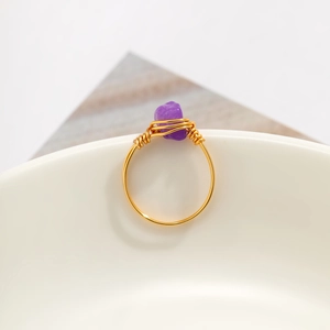 Detail of handmade gold wire-wrapped ring featuring irregular purple amethyst crystal stone
