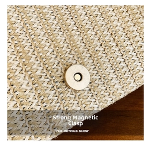 Detail view of the strong gold magnetic buckle on a straw woven handbag with fine texture