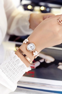 Close-up of women's quartz watch with white flower shaped strap and gold-tone bezel