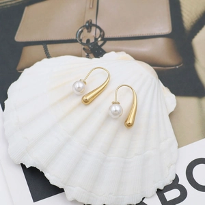 Detailed close-up of 18k gold teardrop pearl earrings displayed on a white shell