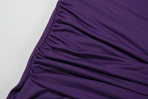 Macro shot of dark purple dress fabric showing elastic shirred texture and fine stitching