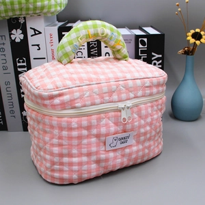 Pink quilted plaid makeup bag with green handle and embroidered Melody text and logo