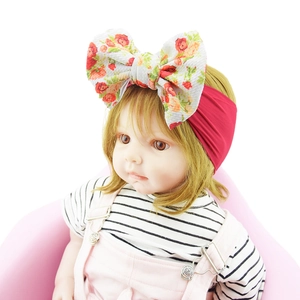 Close-up of baby nylon headband with large red floral print bow on a doll model