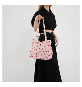 On-shoulder view of pink corduroy tote bag with strawberry print and large capacity