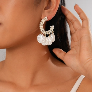 Boucles d'oreilles dorées en C avec zircon et pompons en coquillage sur mannequin
