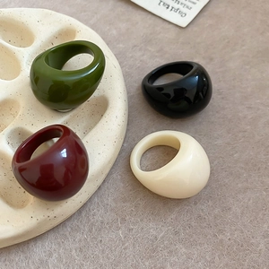 Detail view of four chunky resin rings in vintage colors on a beige display stand