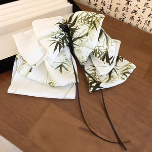 Detailed view of ribbon hair clip with bamboo leaf patterns on a wooden surface