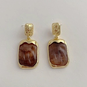 Detail of vintage square resin earrings with gold metal frames and marbled texture