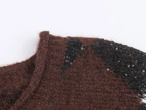 Makroaufnahme: Dunkelbrauner Strickpullover mit Wellentextur und silbernen Pailletten