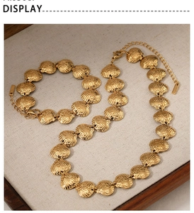Detail of gold seashell necklace and bracelet set on fabric background for a beach look