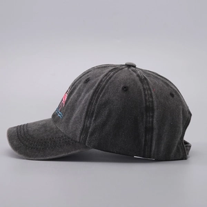 Detail of embroidered pink flamingo on washed dark grey denim baseball cap fabric