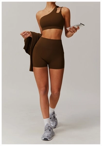 Detail of chocolate brown one-shoulder sports bra and high-waisted shorts with pockets