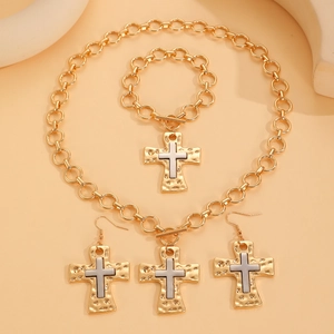 Detailed view of two-tone cross pendants on gold necklace, bracelet, and earrings set