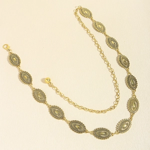 Close-up of vintage bohemian gold waist chain with engraved oval pendants and lobster clasp