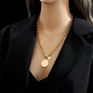 Vintage gold portrait coin pendant necklace on thick chain worn over black suit