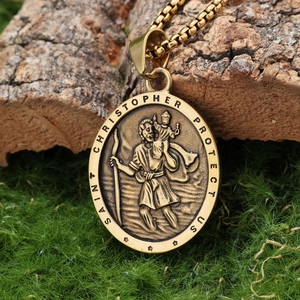 Macro detail of gold Saint Christopher pendant on natural bark and moss background