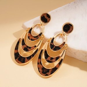Detail view of gold layered oval earrings with faux hair leopard print on natural stone