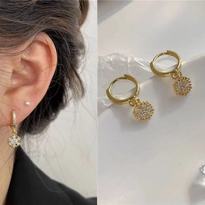 Detailed close-up of golden snowflake hoop earrings with white micro-pave zircons