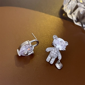 Close-up of asymmetric silver bear earrings with heart locks and zircon stones