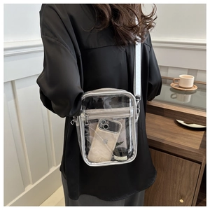Detail of transparent PVC crossbody bag showing storage capacity with phone and cosmetics