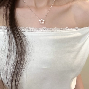 Détail d'un élégant collier pendentif fleur en perles porté sur le cou avec design blanc