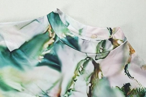 Detail of high neck collar with green and pink abstract ink print on knit fabric