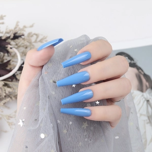 Detail of glossy sky blue extra-long coffin nails on a hand with sequin fabric
