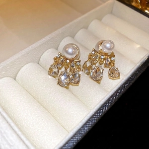 Elegant gold pearl drop earrings with sparkling teardrop crystals on white jewelry box