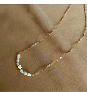 Detail of freshwater pearl necklace with gold heart pendant on silk background