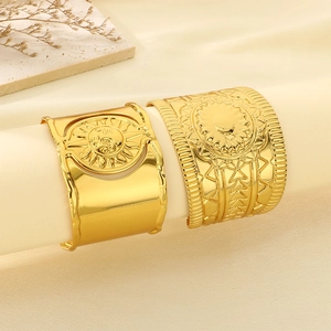Detail of gold wide cuff bracelets featuring sun relief and engraved geometric patterns