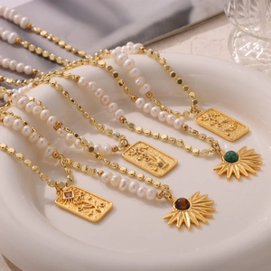 Tiger eye and pearl beaded necklace with gold tarot cards pendants in a white ceramic dish