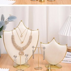 Detail of beige velvet and gold metal jewelry display set on a wooden desktop
