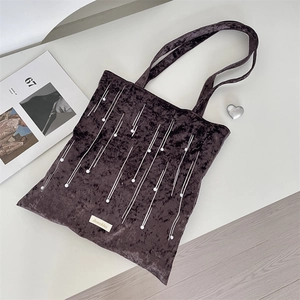 Macro detail of dark purple velvet tote bag with white vertical stitching and pearl accents