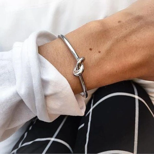 Close-up of a silver knot cuff bracelet worn by a person in a casual street style setting