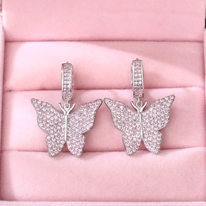 Detailed view of silver butterfly earrings with pink cubic zirconia in a velvet box