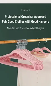 Detailed view of pink flocked hangers with non-slip wide shoulders on a wooden rod