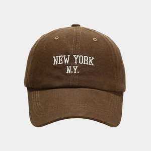 Close-up of white NEW YORK embroidery on dark brown cotton twill baseball cap fabric