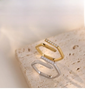 Detail view of gold and silver irregular geometric C-shaped rings with side zircon stones