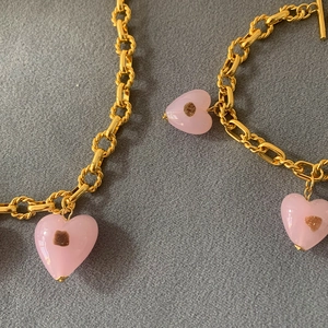 Detail of pink heart pendant with gold chunky chain necklace and T-bar clasp closure