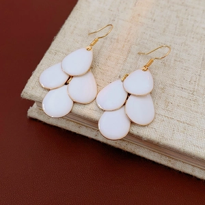Close-up of white layered teardrop petal tassel earrings with golden ear hooks