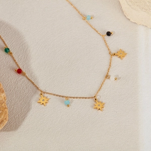 Detailed close-up of a gold star necklace with colorful beads on a beige texture