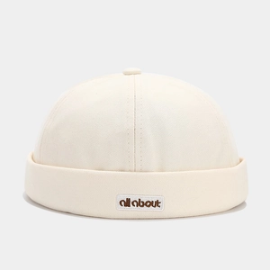 Detail of cream cotton docker hat featuring an all about embroidery patch and rolled brim