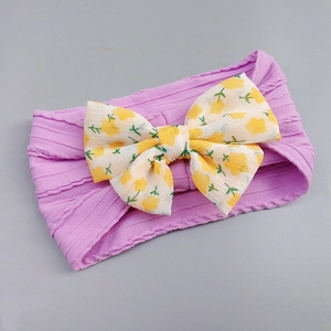 Detail of purple nylon headband featuring a yellow floral print bow for infants
