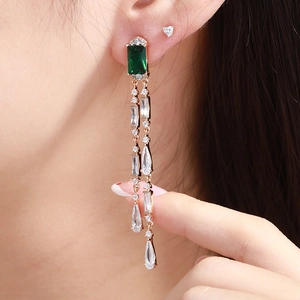 Macro shot of long emerald green gemstone drop earrings with sparkling zircon tassels