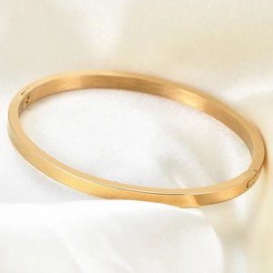 Minimalist 4mm gold stainless steel open bangle for women on elegant silk fabric background