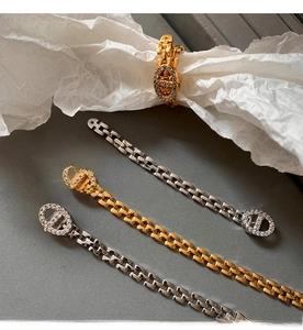 Detail shot of gold chain bracelets with zircon studs and matching oval link ring