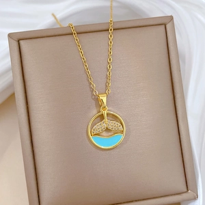 Macro detail of gold mermaid tail pendant with blue enamel and sparkling diamonds